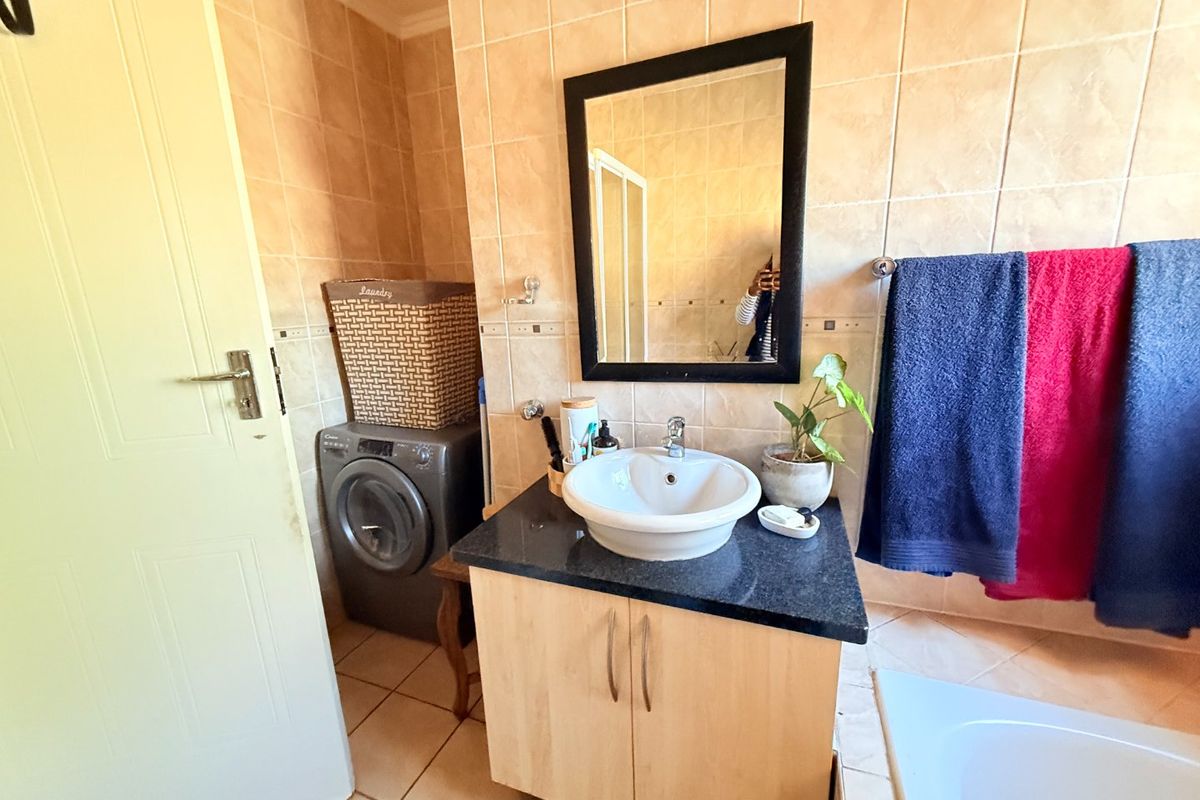 A functional bathroom featuring a vanity with a vessel sink, granite countertop, tiled wall finishes, and a built-in bathtub.