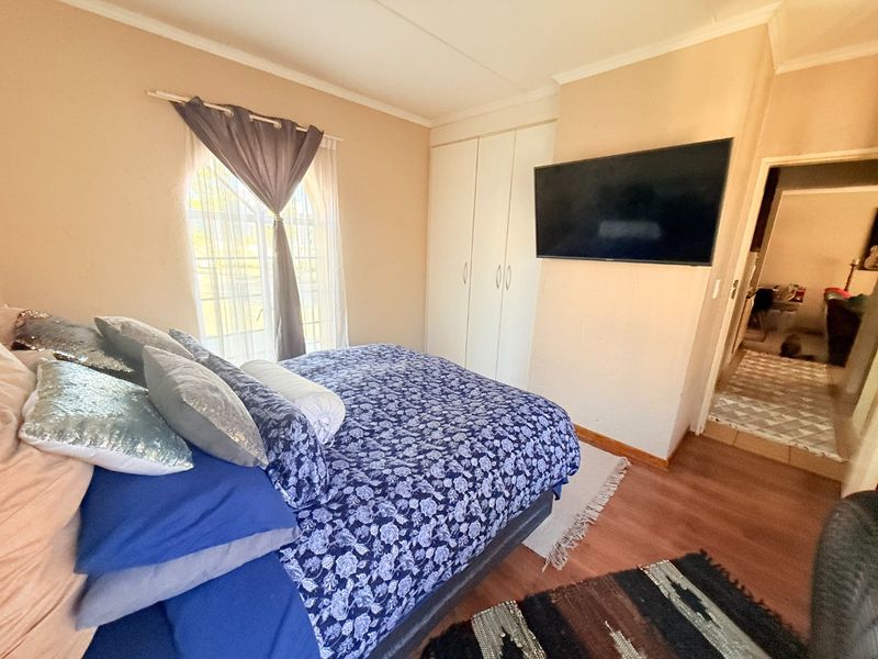 A functional bedroom featuring laminate flooring, a built-in wardrobe, and coved ceiling details, providing a comfortable and practical living space.