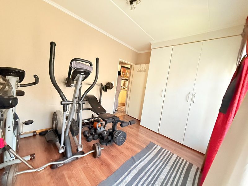 A bedroom featuring laminate flooring and built-in cupboards, currently utilized as a home gym space.