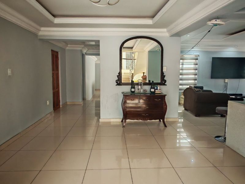 Spacious open-plan living area featuring large format floor tiles, decorative crown molding, and a recessed ceiling design with modern lighting.