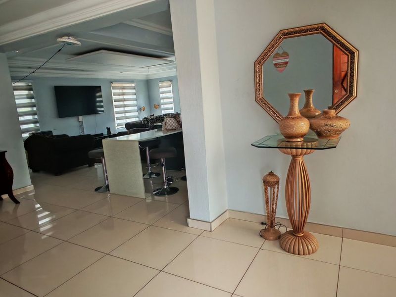 Spacious open-plan living area featuring tiled flooring, a central breakfast bar, and recessed ceiling details, creating a bright and functional layout.