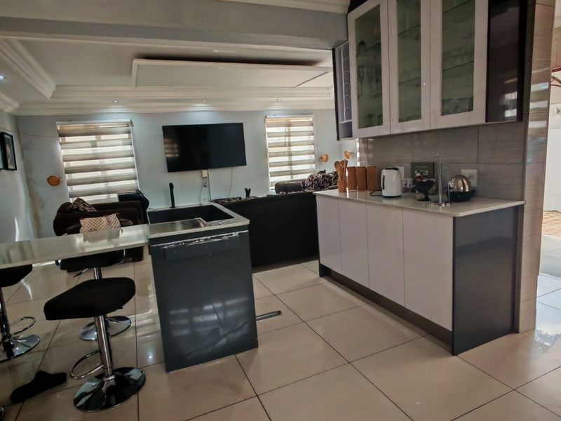 Open-plan living and kitchen area featuring modern cabinetry, stone countertops, a breakfast bar, and tiled flooring throughout.