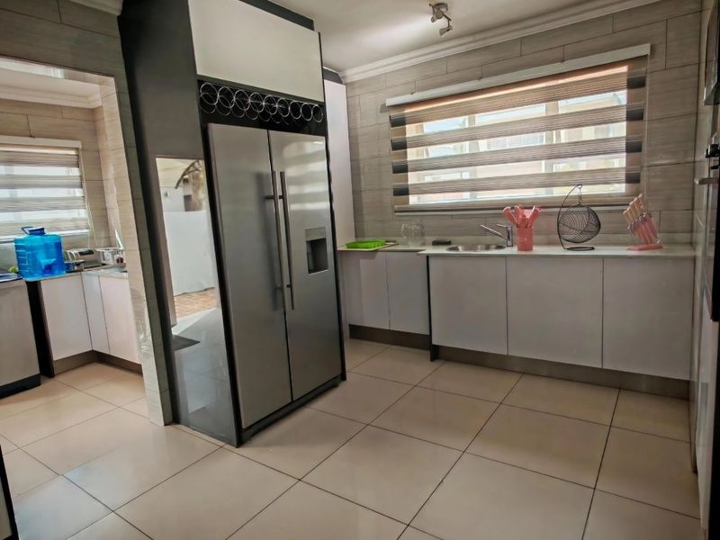 A functional kitchen featuring tiled flooring, built-in cabinetry, and a stainless steel sink, with visible ceiling damage requiring repair.