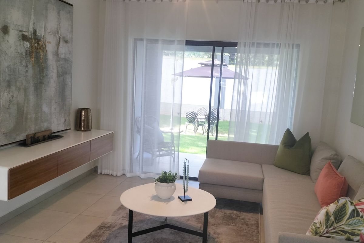 A bright living room featuring large sliding glass doors that open onto a private patio and garden area, creating a seamless indoor-outdoor flow.