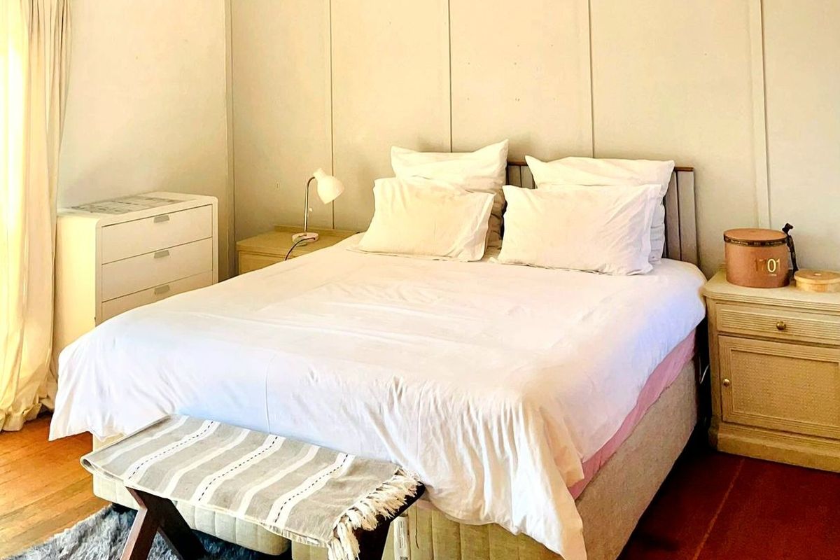A bedroom featuring timber flooring and a panelled feature wall, offering a neutral foundation for interior design.