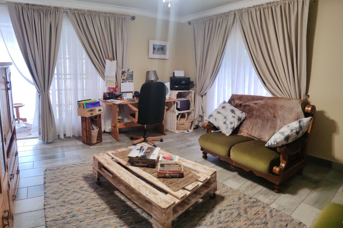 A living room featuring tiled flooring and dual sliding glass doors that provide access to the outdoor area.
