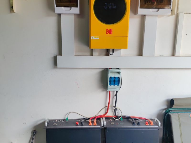 A wall-mounted solar inverter and battery storage system installation, featuring integrated electrical distribution boards for efficient power management.
