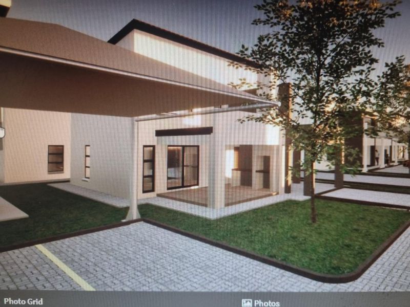 Modern residential exterior featuring a paved driveway, shade sail carport, and landscaped garden area with contemporary architectural finishes.