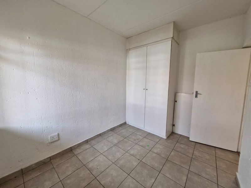 An empty bedroom featuring tiled flooring and a built-in wardrobe, offering a blank canvas for potential renovation or staging.