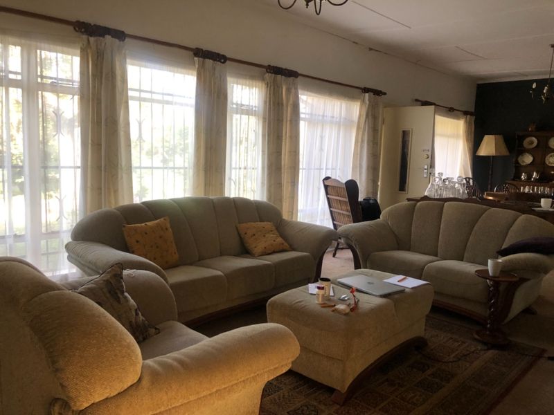 Spacious living room featuring large windows with security bars and natural light, offering a comfortable area for relaxation.