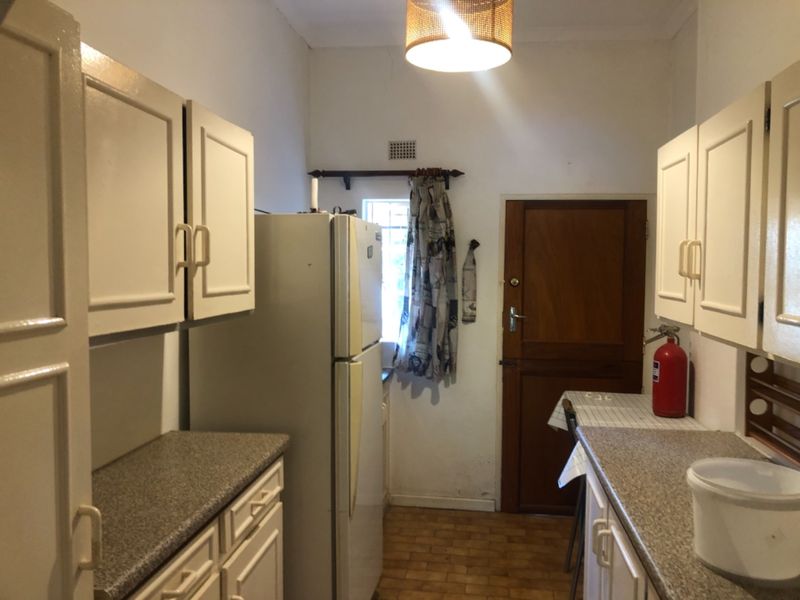 A compact kitchen featuring laminate countertops, built-in cabinetry, and tiled flooring, offering a functional layout with potential for modern updates.