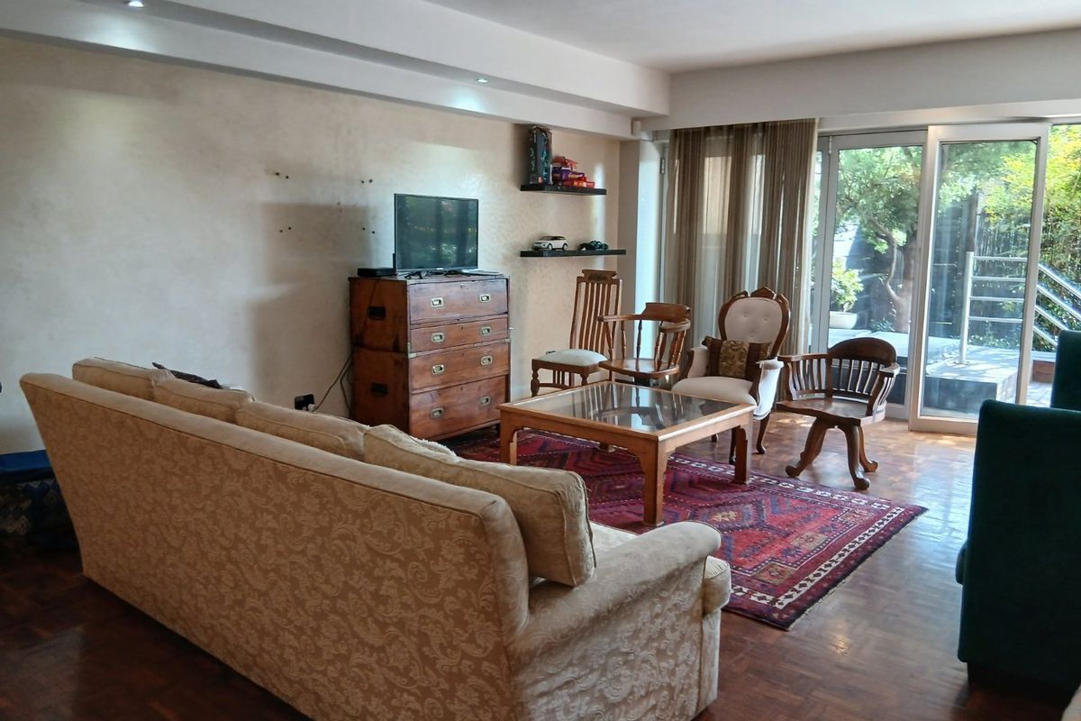 Spacious living room featuring warm parquet flooring, recessed ceiling lighting, and large sliding glass doors that provide access to the outdoor patio area.