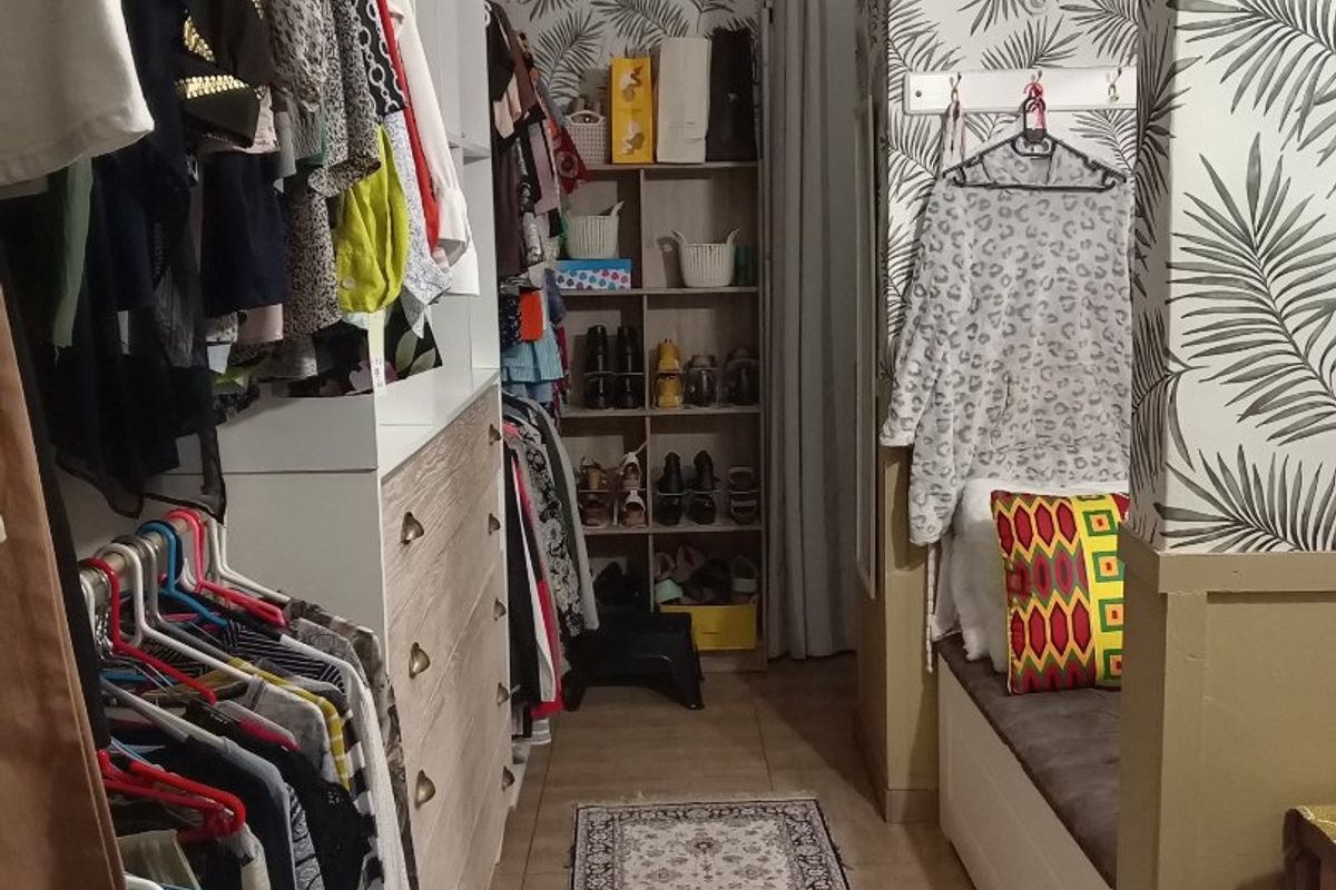 A walk-in closet or dressing area featuring extensive built-in cabinetry, shelving, and a built-in bench seat with patterned wallpaper accents.