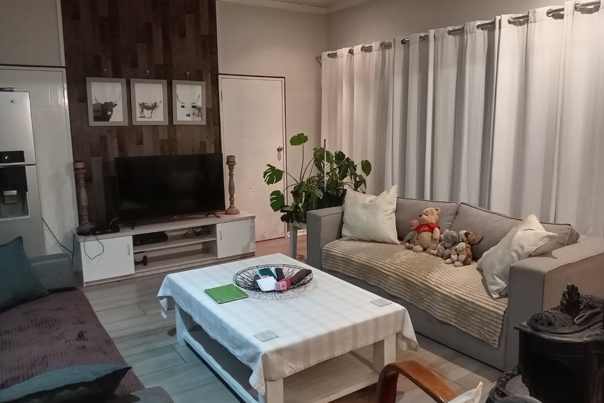 A comfortable living room featuring a wood-look accent wall, tiled flooring, and a built-in wood-burning stove, creating a warm and inviting atmosphere.