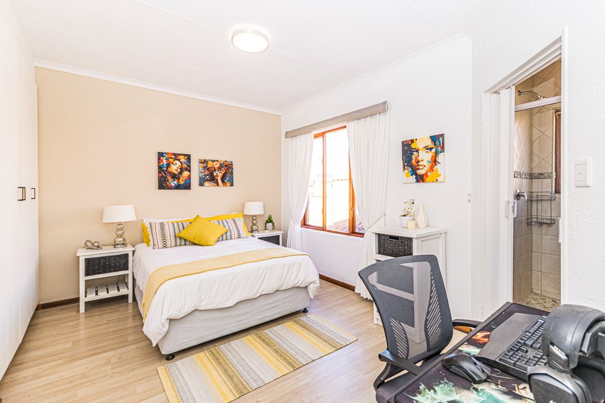 A well-maintained bedroom featuring laminate flooring, a built-in wardrobe, and an attached en-suite bathroom with a shower.