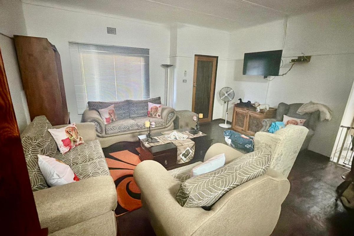 A living room space featuring neutral walls, tiled flooring, and window blinds, offering a functional area for relaxation.