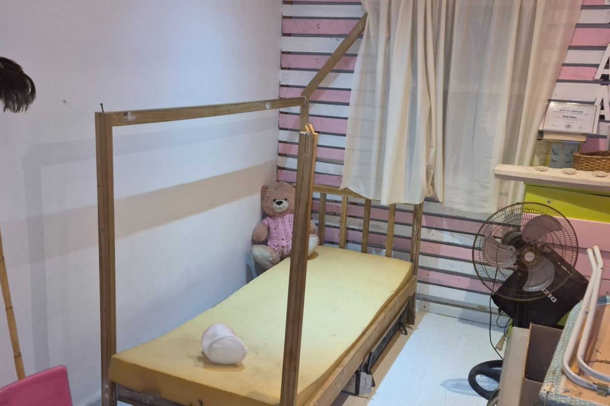 A small bedroom featuring timber wall cladding and basic finishes, currently requiring cosmetic updates and maintenance.