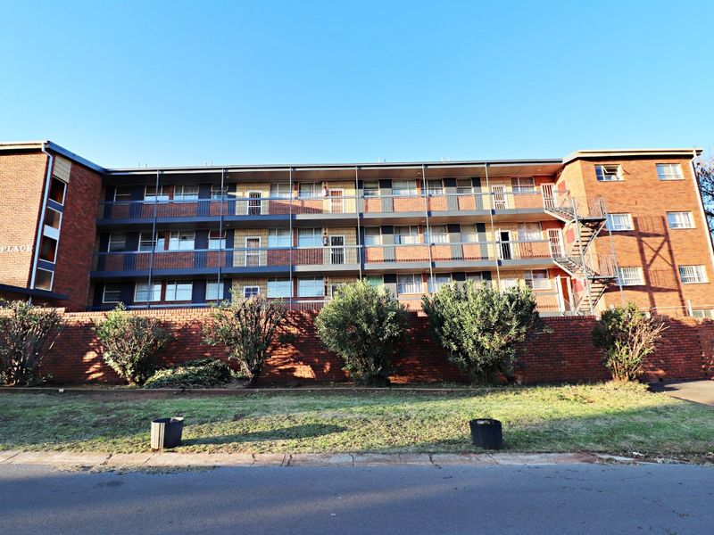 Front elevation of a multi-story apartment complex featuring brick construction, external metal balconies, and an external staircase.