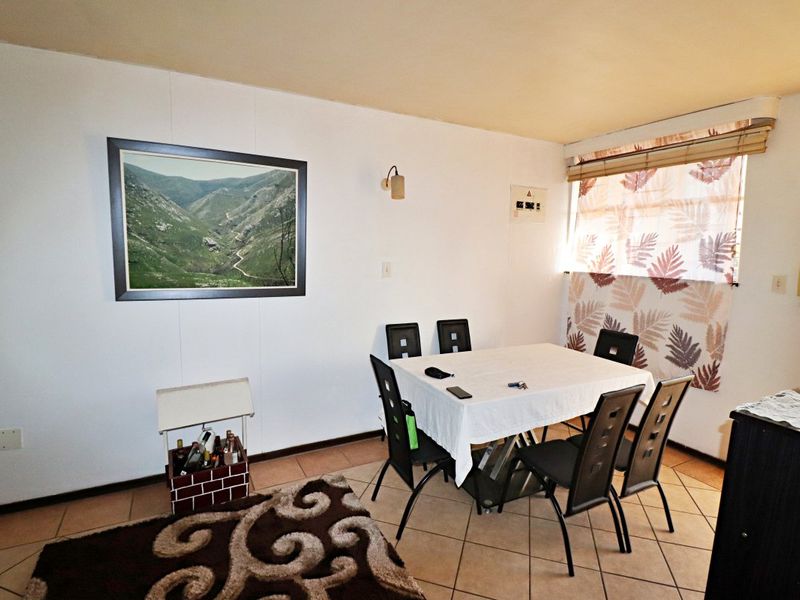 A functional dining area featuring tiled flooring and a wall-mounted light fixture, providing a practical space for meals.