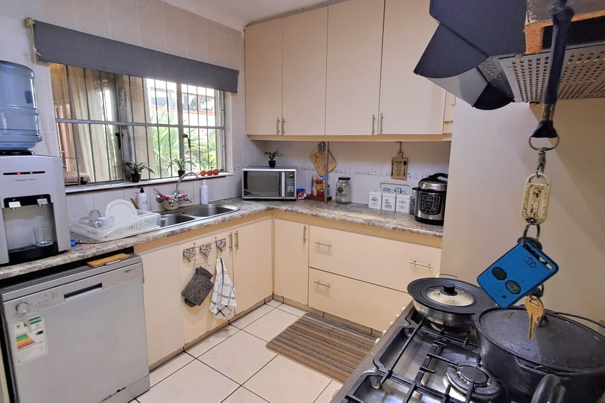 Functional kitchen featuring laminate cabinetry, stone-look countertops, double basin sink, and a built-in gas hob with overhead extractor fan.