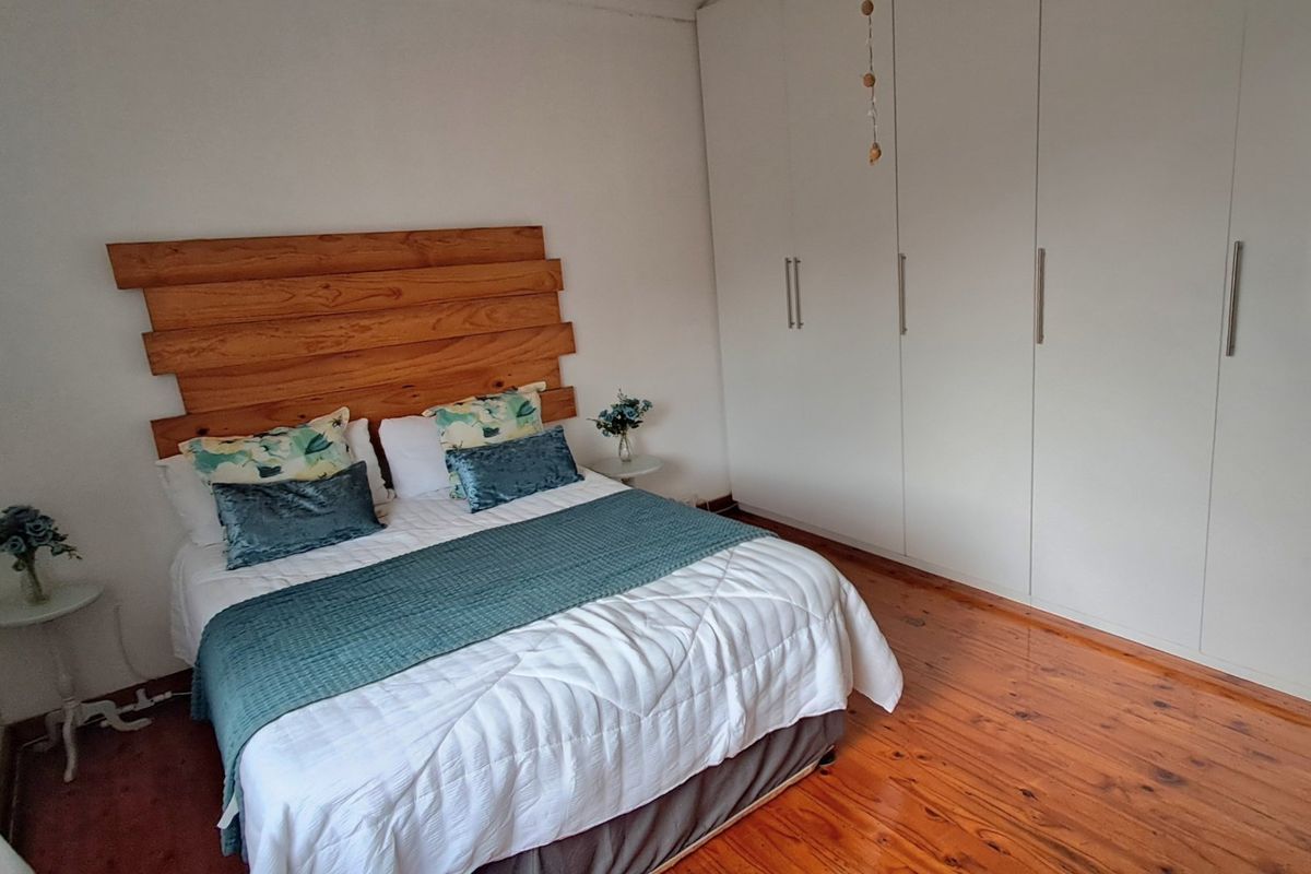 A well-maintained bedroom featuring polished wooden flooring and extensive floor-to-ceiling built-in wardrobes providing ample storage space.