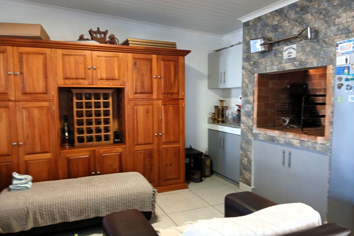 Living area featuring a built-in brick braai with stone cladding, extensive wooden cabinetry, and tiled flooring.