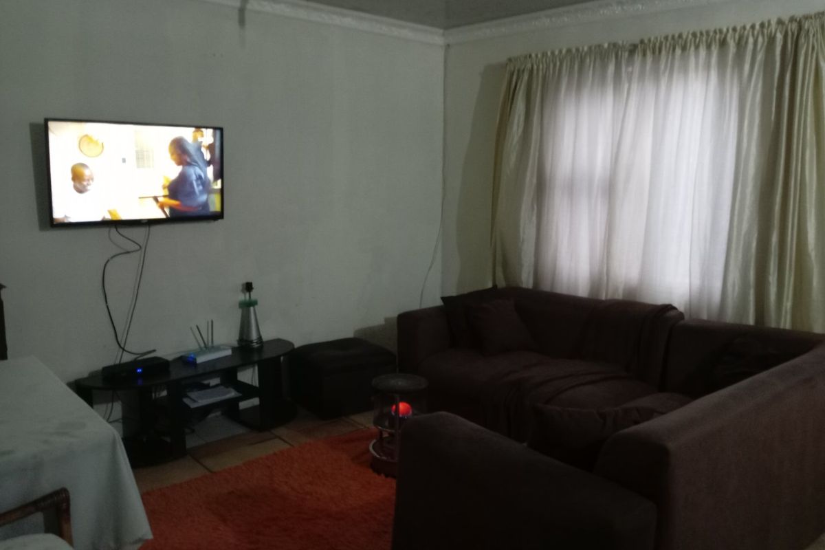 A living room featuring tiled flooring and decorative ceiling cornicing, providing a functional space for relaxation.