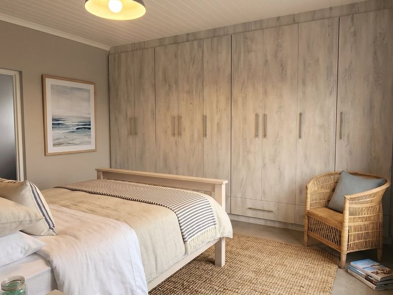 A well-maintained bedroom featuring extensive built-in cupboards with a light wood finish, tongue and groove ceiling, and a neutral color palette.