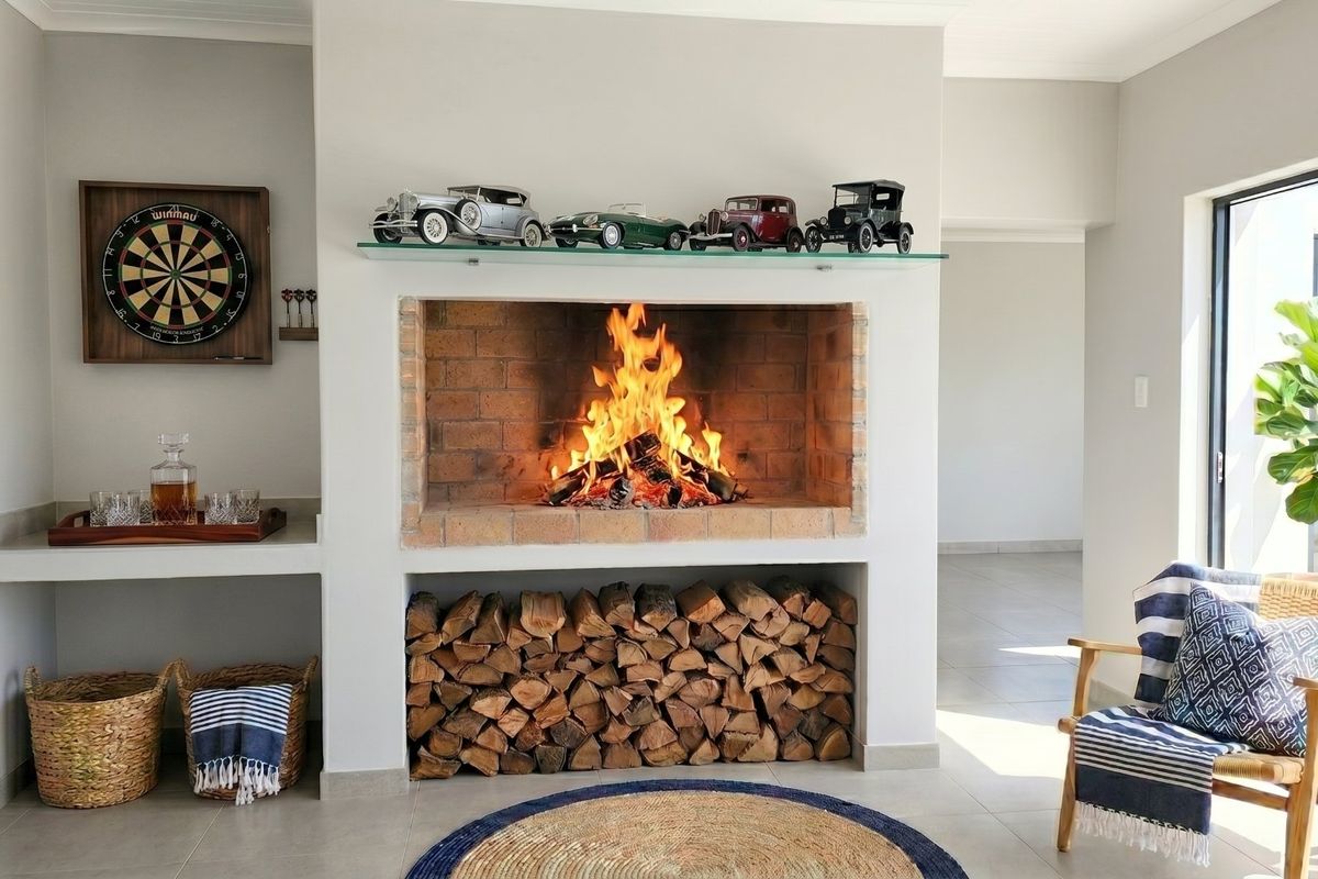 A cozy living room featuring a prominent built-in brick fireplace with integrated log storage and neutral tiled flooring.