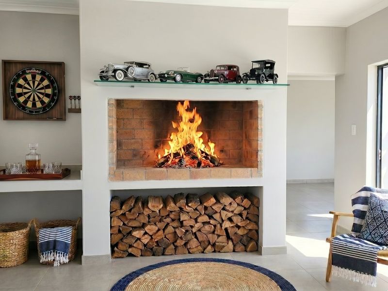 A cozy living room featuring a prominent built-in brick fireplace with integrated log storage and neutral tiled flooring.