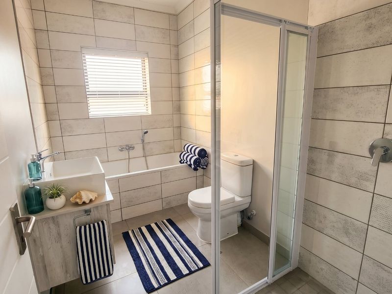 Modern bathroom featuring a built-in vanity with vessel sink, a bathtub, a separate shower enclosure, and neutral wall tiling.