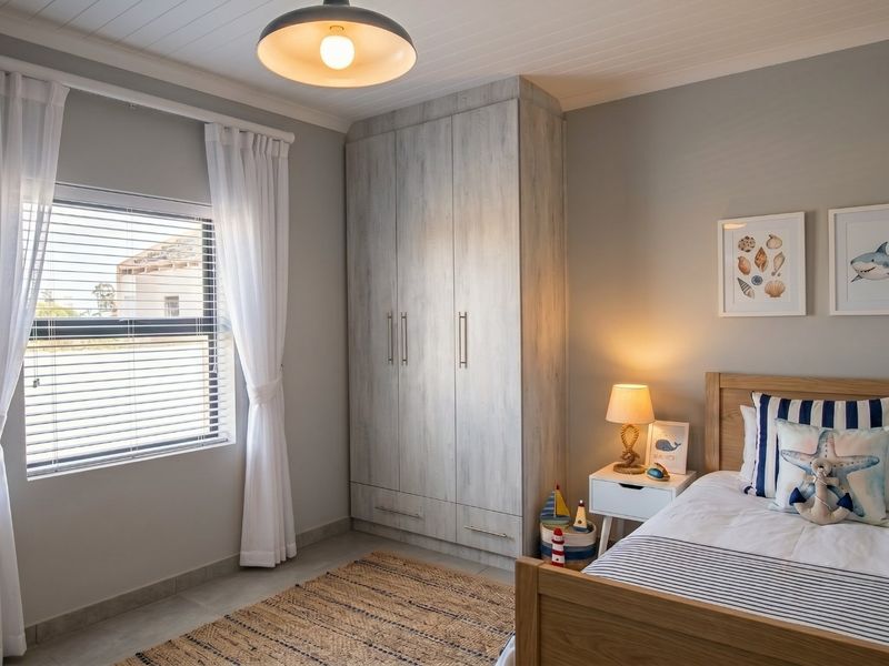 A well-maintained bedroom featuring neutral wall tones, tiled flooring, a built-in wardrobe, and a classic tongue and groove ceiling finish.
