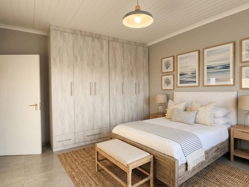 A well-maintained bedroom featuring built-in wardrobes, tiled flooring, and a classic tongue and groove ceiling finish.