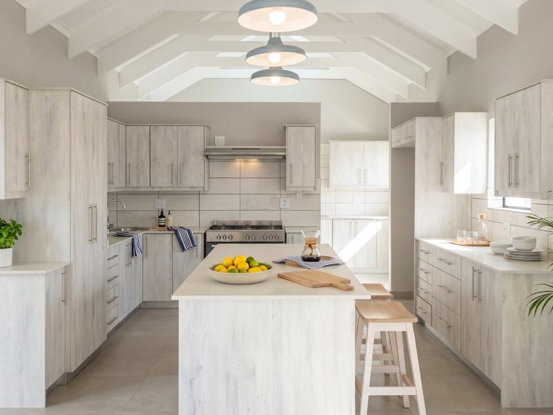 Modern, bright kitchen featuring a central island, light wood-grain cabinetry, vaulted ceilings, and high-quality finishes throughout.