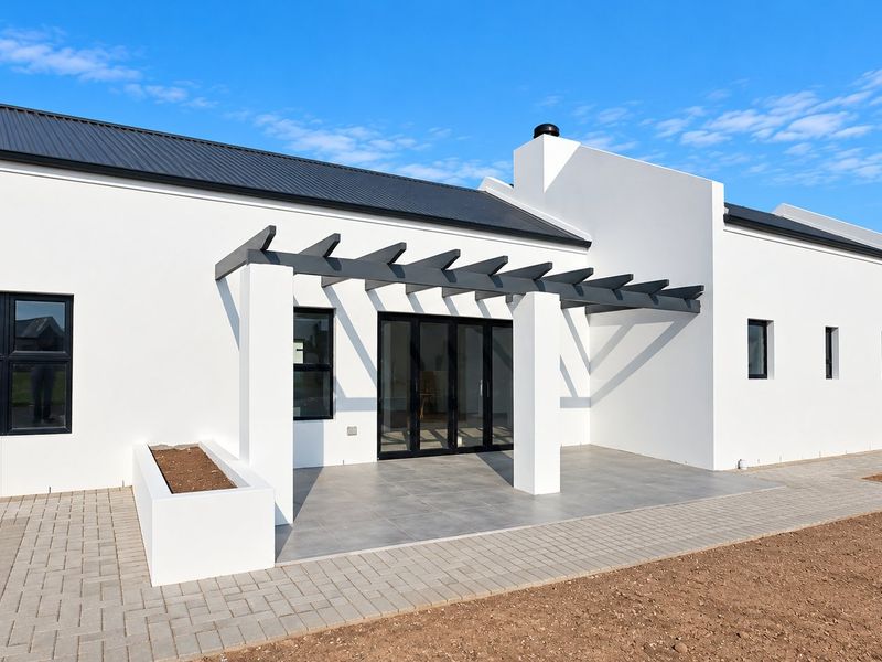 Modern rear exterior featuring a covered tiled patio with a pergola, built-in planter, and clean white facade with dark metal roofing.