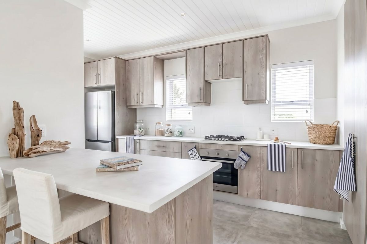 Modern kitchen featuring light wood cabinetry, stone countertops, a central island, and integrated appliances with a clean, contemporary aesthetic.