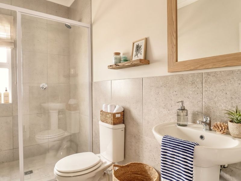 A modern, well-maintained bathroom featuring a walk-in shower, pedestal basin, and neutral tiled finishes throughout.