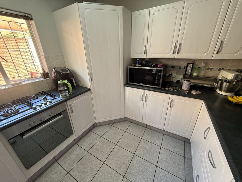 A functional kitchen featuring white cabinetry, dark laminate countertops, a built-in oven with gas hob, and tiled flooring.