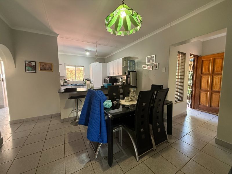 Open plan dining and kitchen area featuring tiled flooring, white cabinetry, a breakfast bar, and a decorative stained glass pendant light.