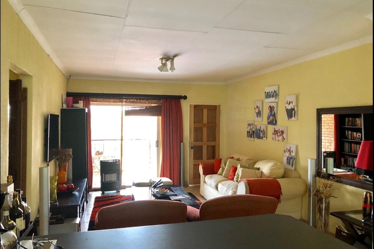 A living room featuring a sliding glass door leading to an outdoor area, with standard ceiling tiles and timber door finishes.