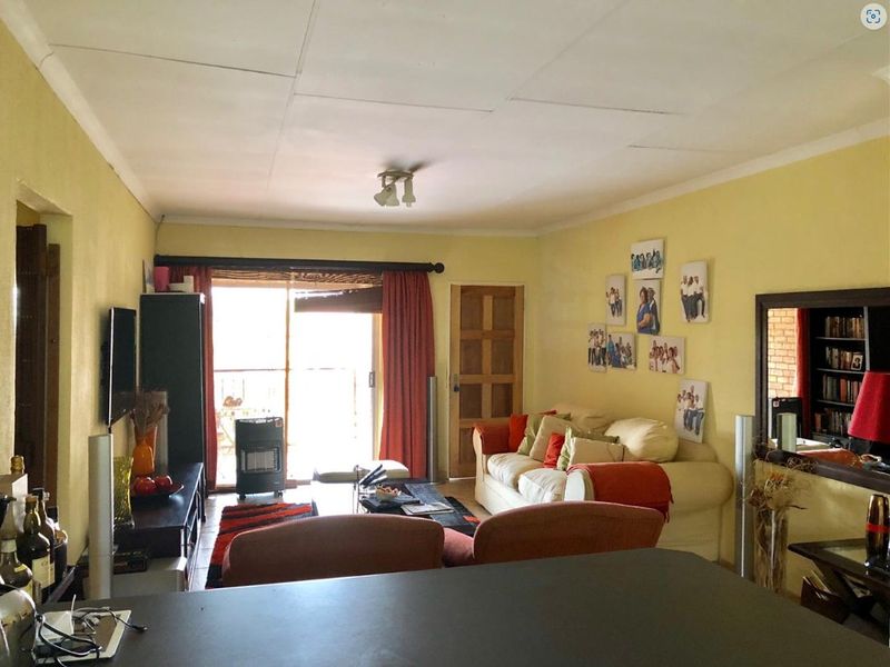 A living room featuring a sliding glass door leading to an outdoor area, with standard ceiling tiles and timber door finishes.