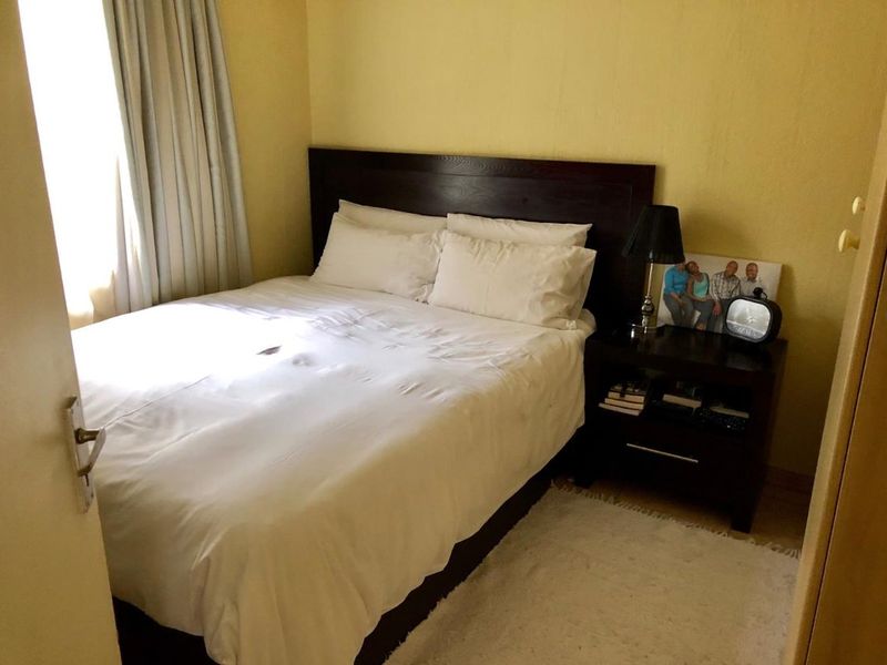 A standard bedroom featuring a built-in headboard and neutral wall finishes, offering a functional space for rest.