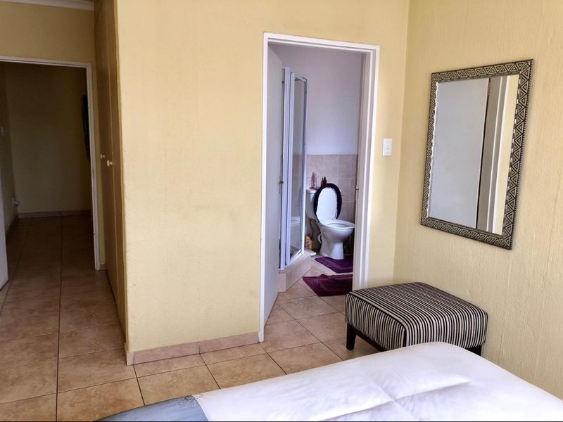 Bedroom featuring tiled flooring, built-in cupboards, and direct access to an en-suite bathroom.