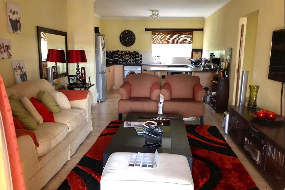 Open-plan living area featuring a combined lounge and kitchen space with tiled flooring and functional cabinetry.