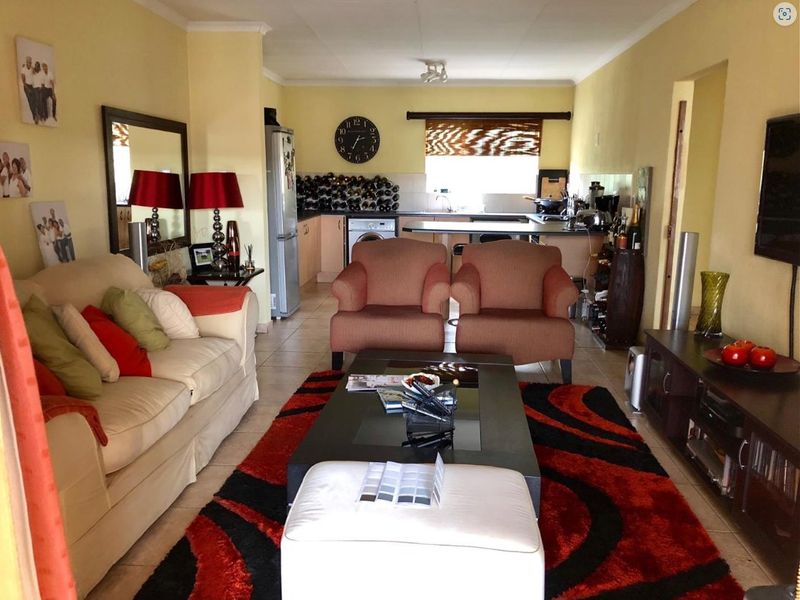 Open-plan living area featuring a combined lounge and kitchen space with tiled flooring and functional cabinetry.