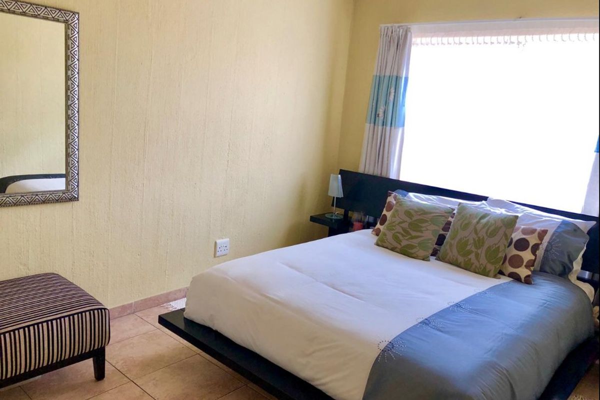 A bedroom featuring tiled flooring and textured walls, offering a functional space with natural light from the window.