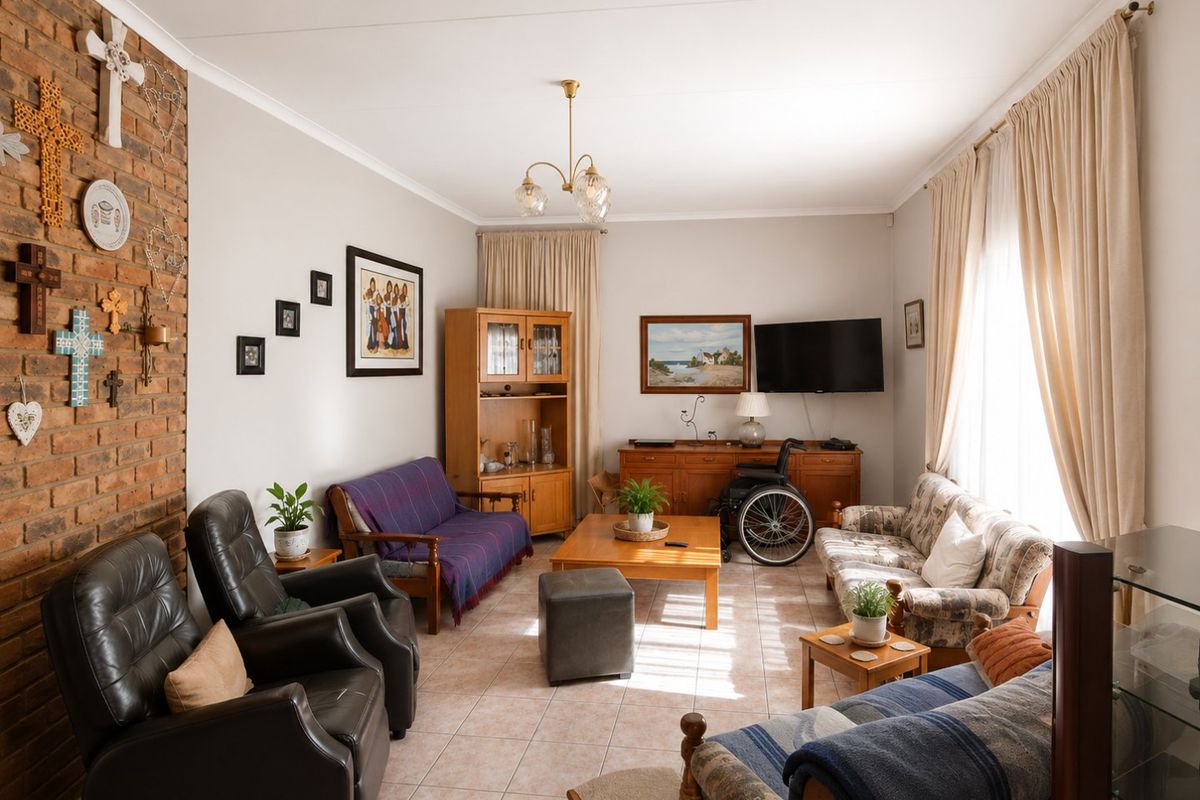 A spacious living room featuring an exposed brick accent wall, neutral tiled flooring, and large windows with curtain treatments.