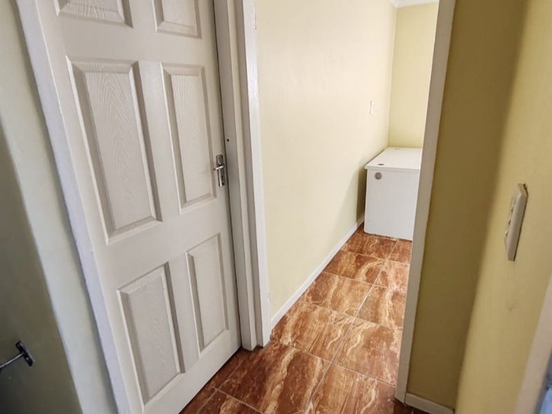 A functional hallway area featuring tiled flooring and a classic panelled door, leading into an adjacent utility space.