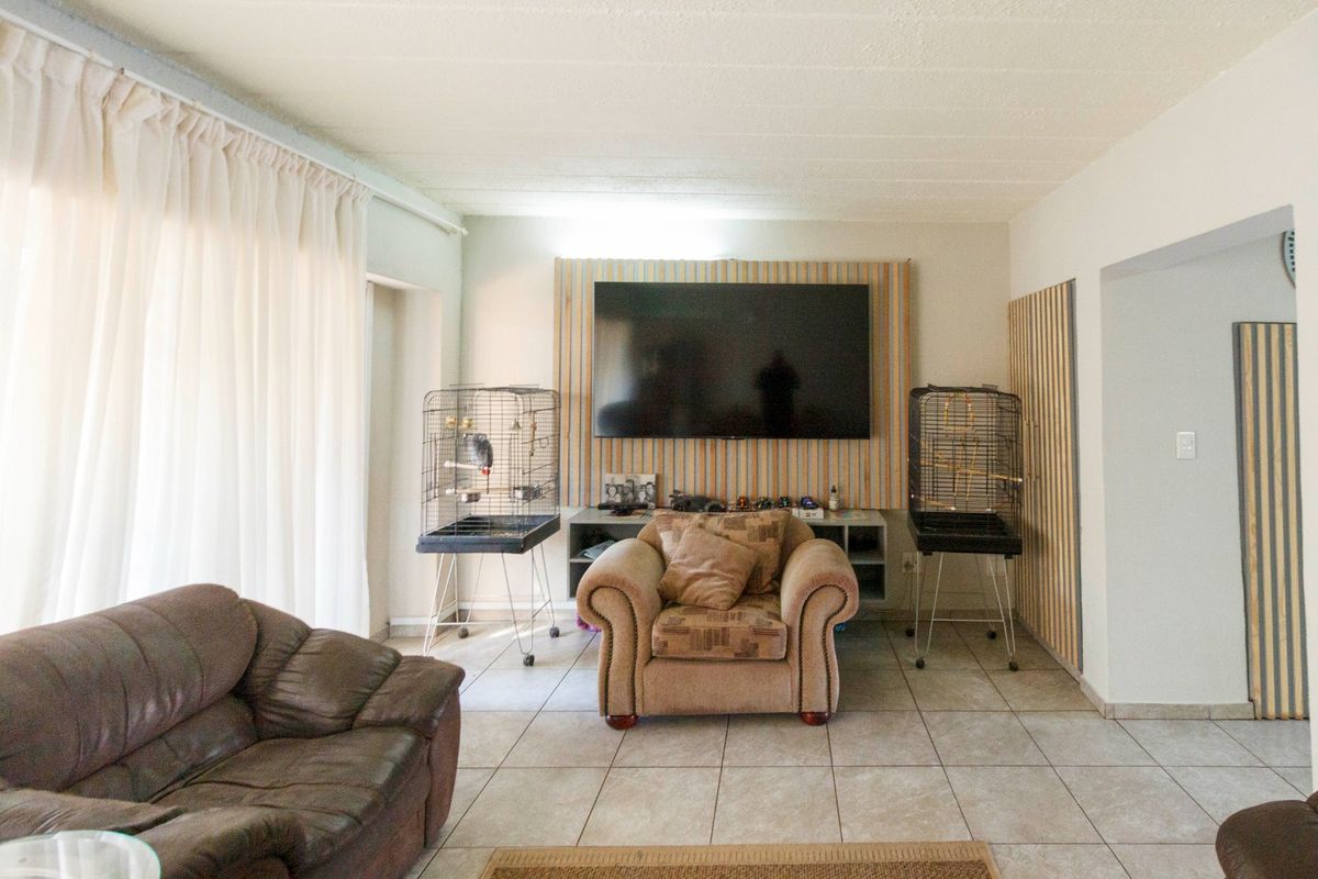 A living room featuring tiled flooring and a decorative slatted timber feature wall with integrated shelving.