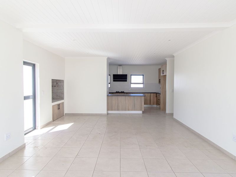 Spacious open-plan living area featuring tiled floors, a tongue and groove ceiling, and a modern kitchen with built-in cabinetry and an island.